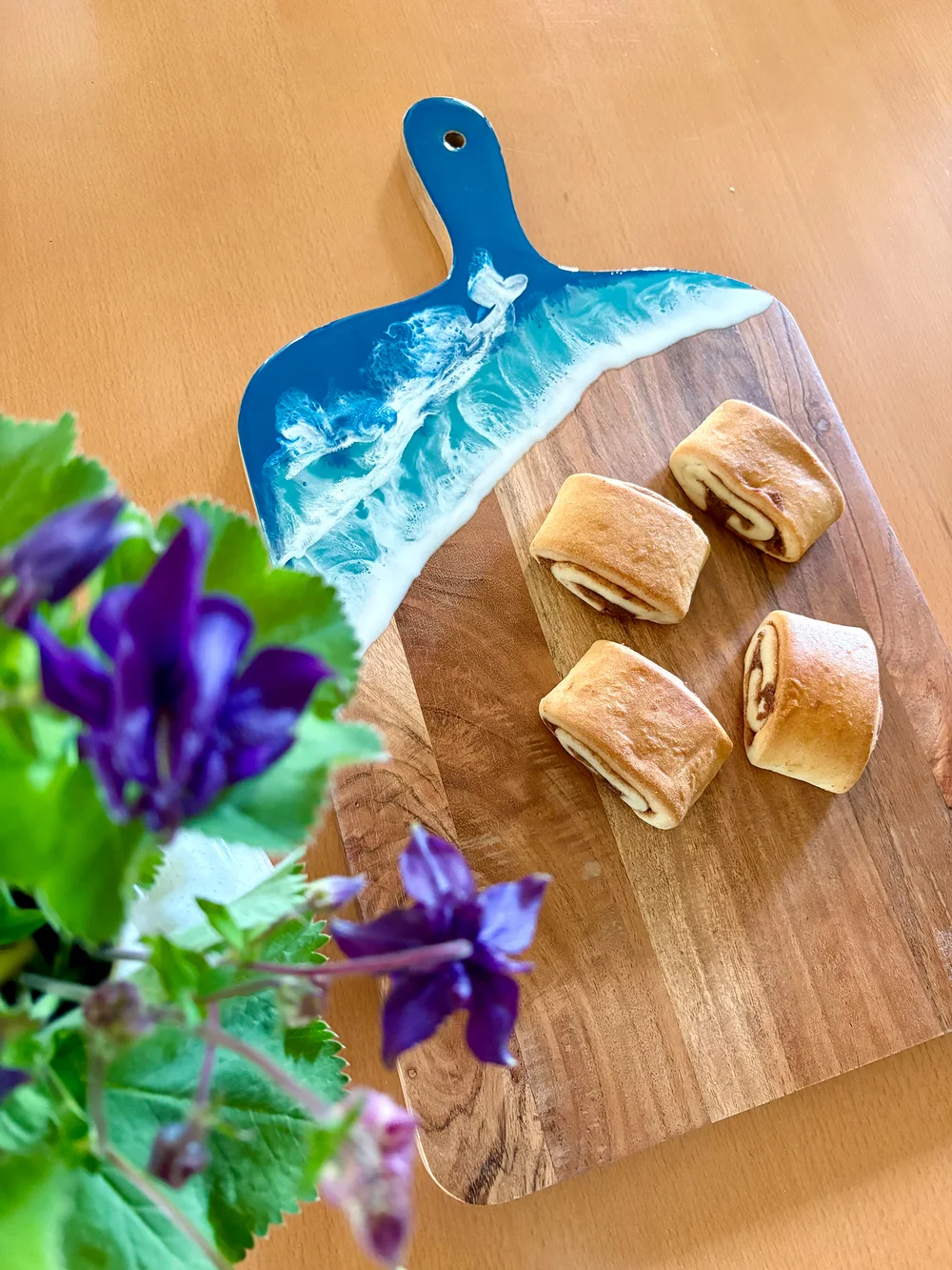 Servierbrett aus Holz mit blauen Wellen und Gebäck